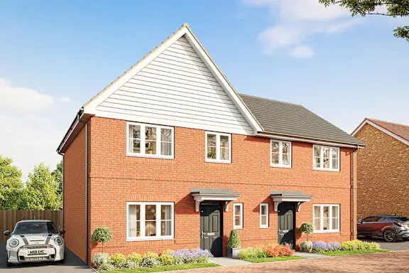 A white car is parked in front of a red brick building.